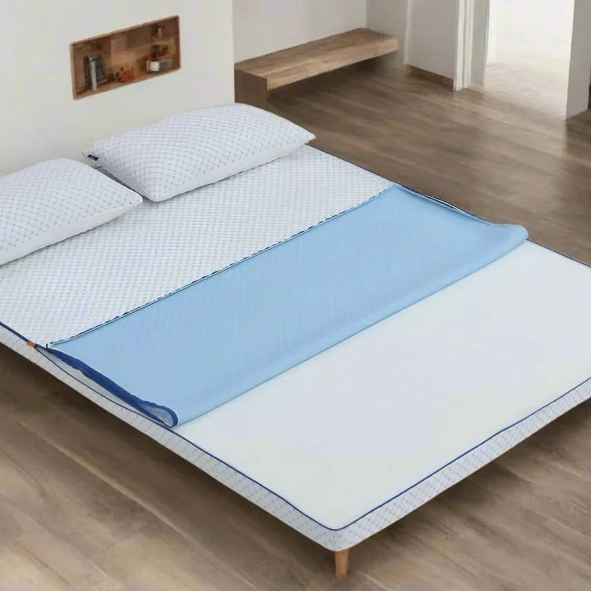White Dreams to Go Kool Mattress Topper with blue cooling layer partially folded back, on a wooden bed frame with two pillows.